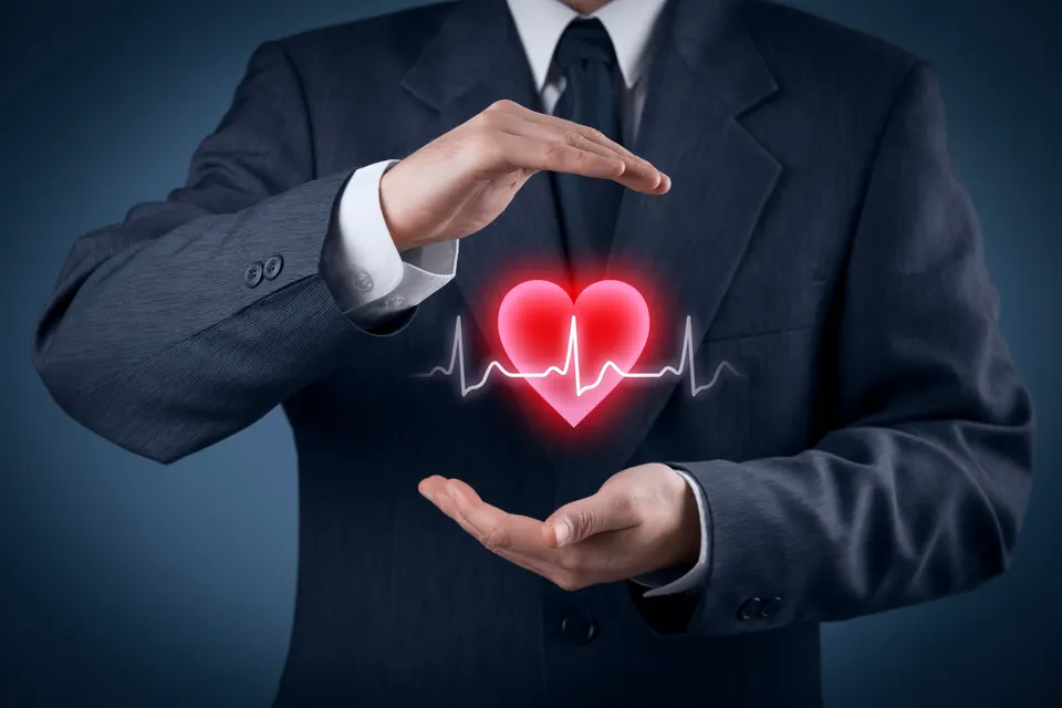 building-company Businessman in a suit shields a glowing heart with a heartbeat line between his hands, symbolizing heart health protection,